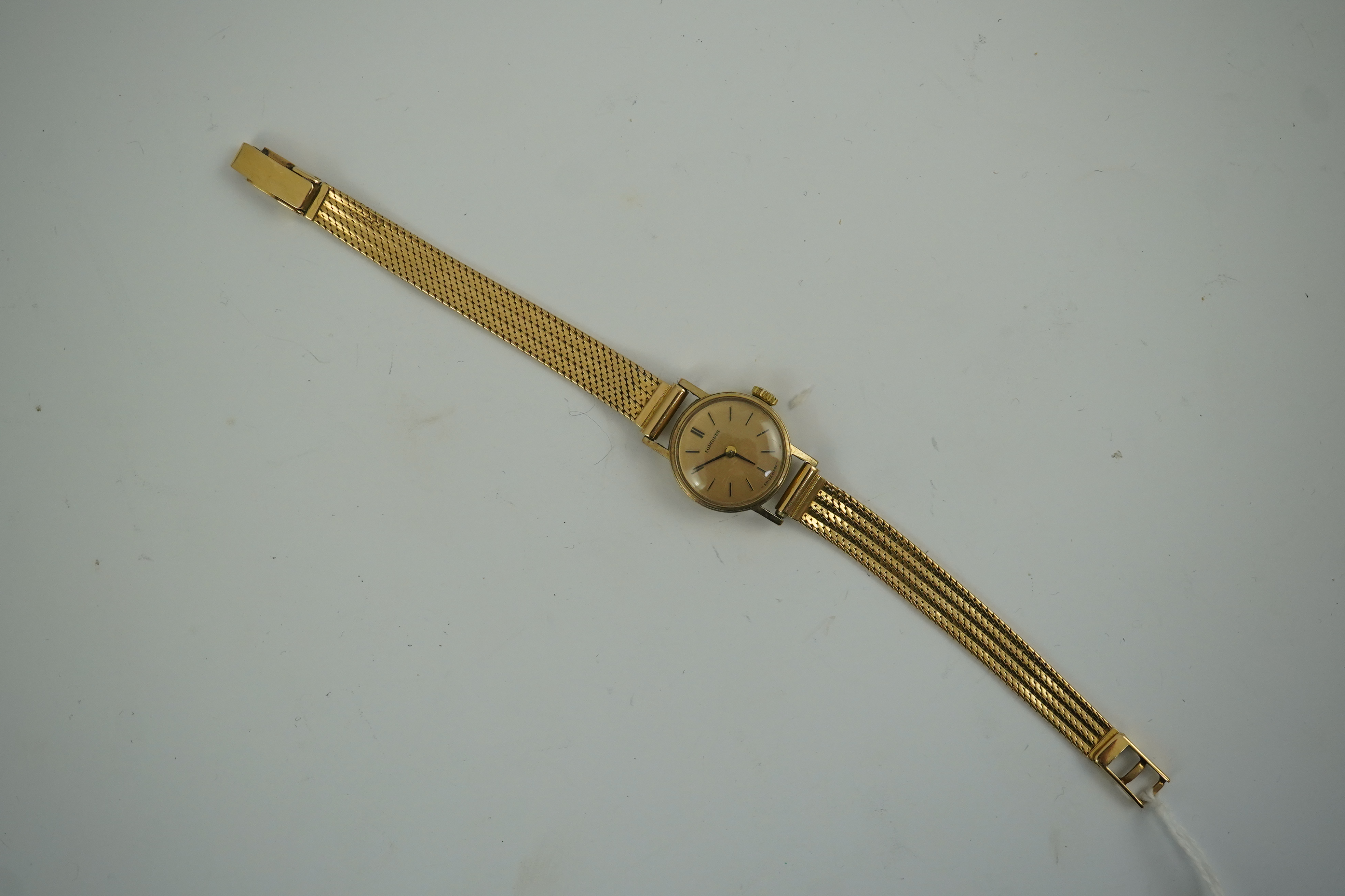 A lady's modern 9ct gold Longines manual wind wrist watch, on an Italian 18k gold bracelet